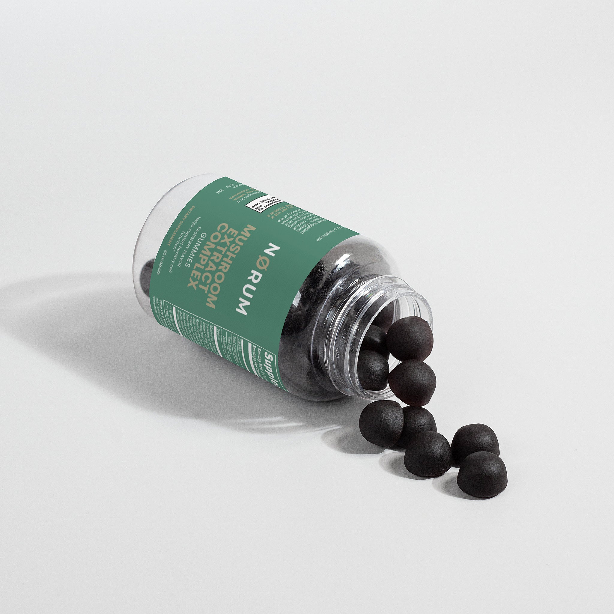 Mushroom extract supplement gummies spilling from a labeled clear bottle on a white background